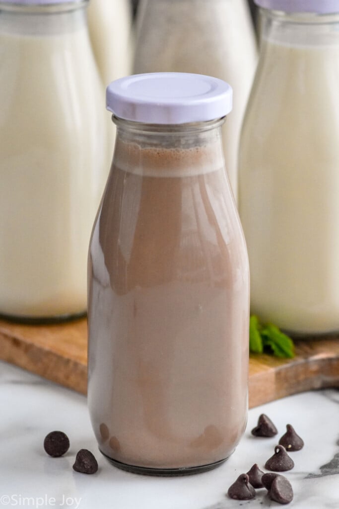 Close up photo of a jar of chocolate Homemade Coffee Creamer. Chocolate chips sprinkled on counter beside jar.