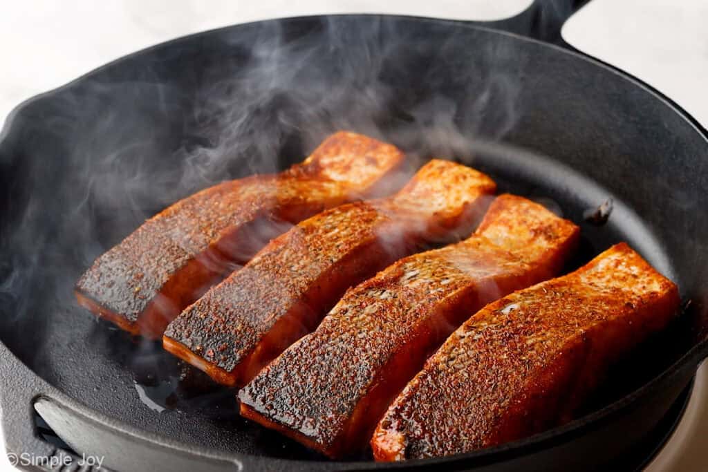 salmon being seared in a cast iron skillet