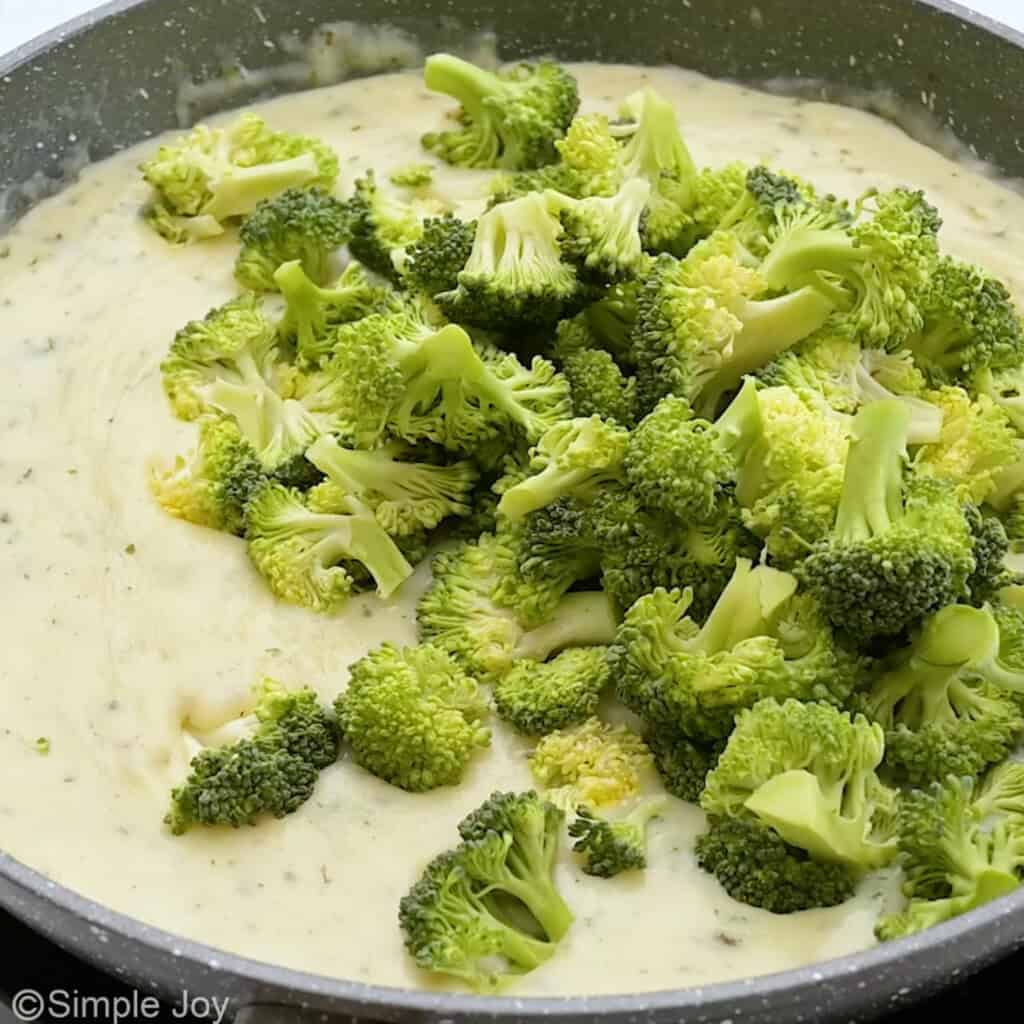 broccoli added to a cream sauce in a skillet