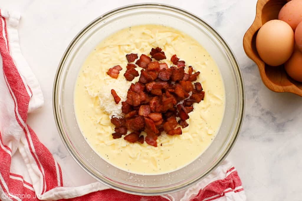 overhead of a bowl of whisked eggs, milk, cheese, and bacon to make quiche lorraine