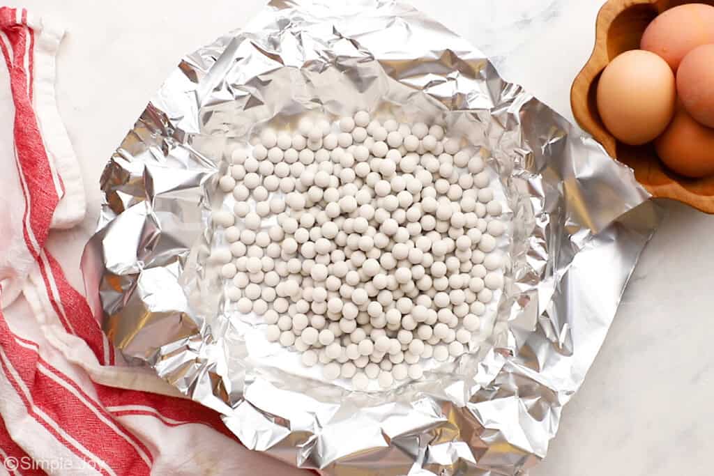 a pie crust lined with aluminum foil and weighed down with ceramic pie weights