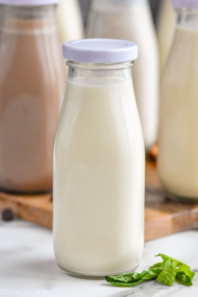 Close up photo of a jar of mint Homemade Coffee Creamer. Other bottles of Homemade Coffee Creamer in the background.