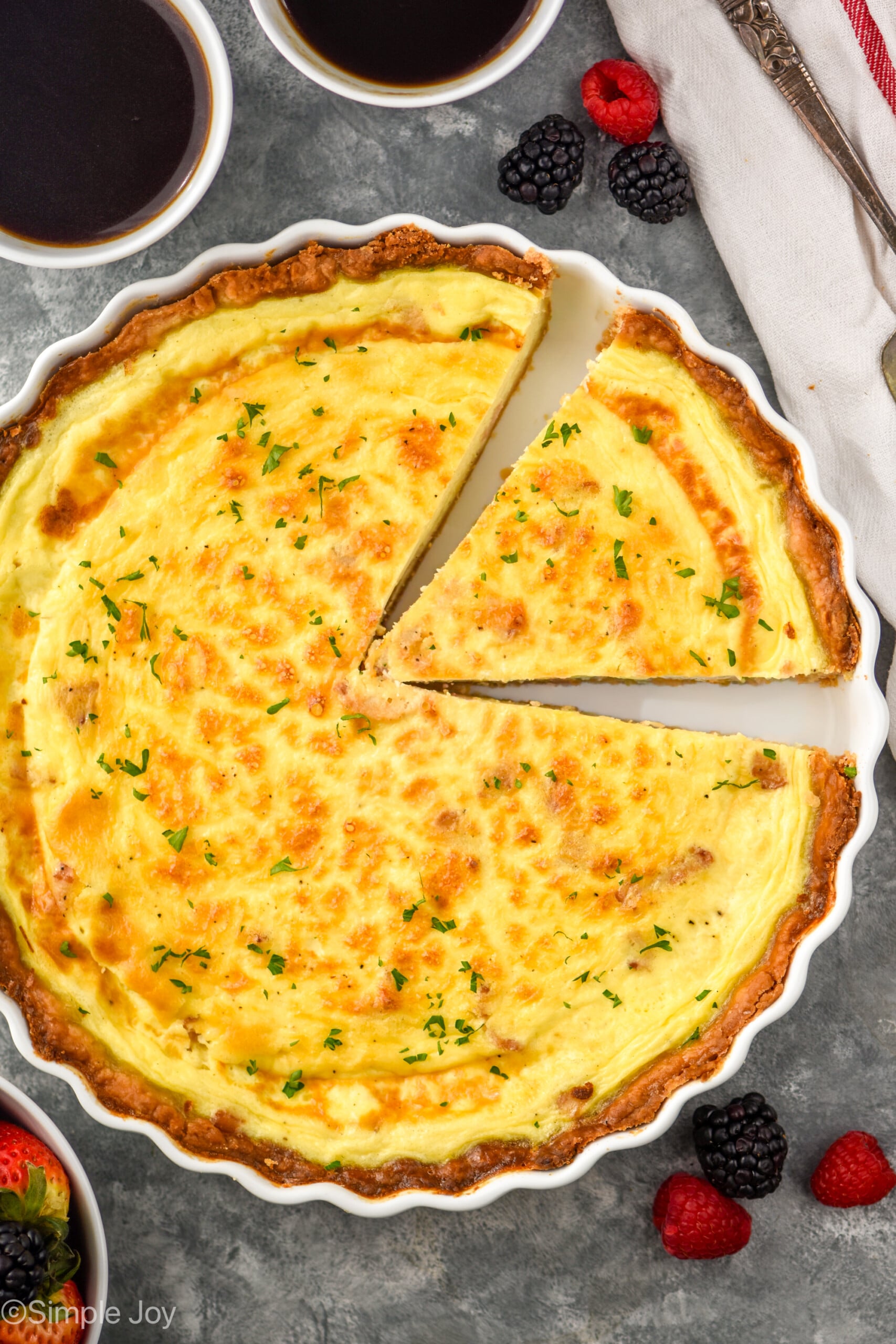 overhead of quiche Lorraine with one slice cut and ready to come out