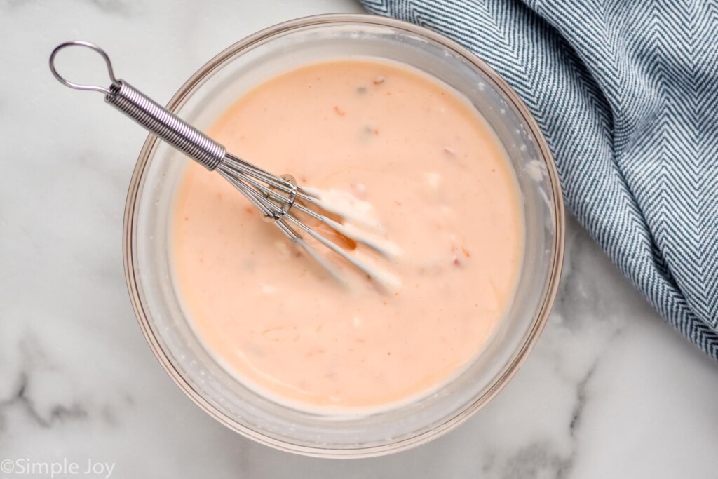 Overhead photo of a bowl of Bang Bang Sauce with a whisk for mixing ingredients.