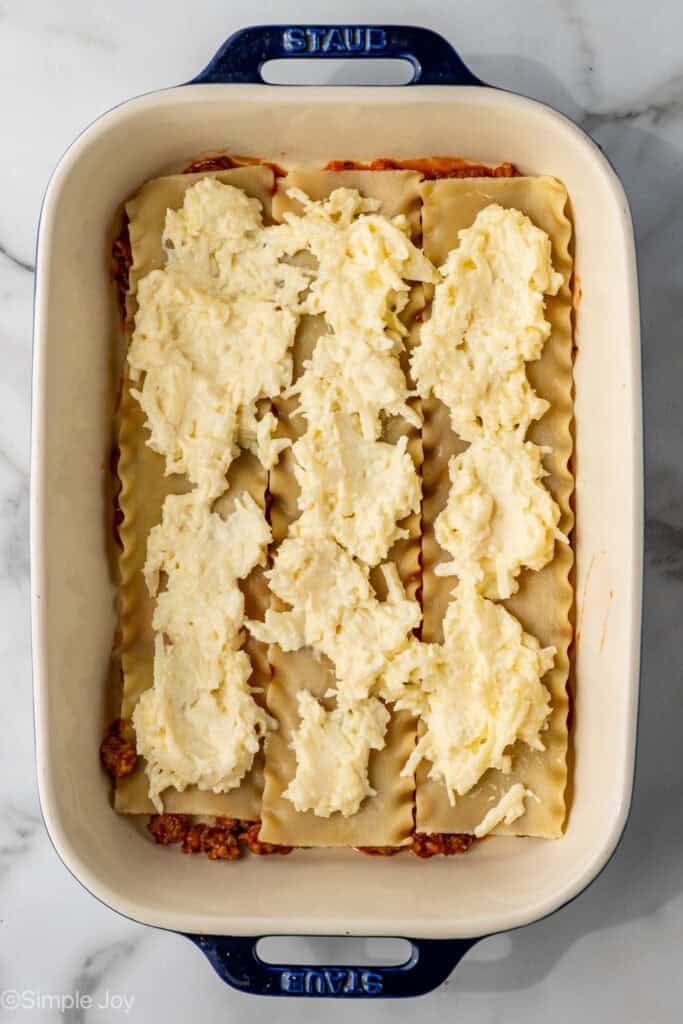overhead of ricotta cheese filling mixture spread over lasagna noodles