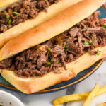 Pinterest graphic for French Dip Sandwich recipe. Image is overhead photo of a platter of French Dip Sandwiches with a bowl of french fries. Text says, "super easy French Dip Sandwiches simplejoy.com"