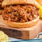 Pinterest graphic for Homemade Sloppy Joes recipe. Image is photo of Homemade Sloppy Joes sandwiches with glasses of beer in the background. Text says, "Sloppy Joes simplejoy.com"