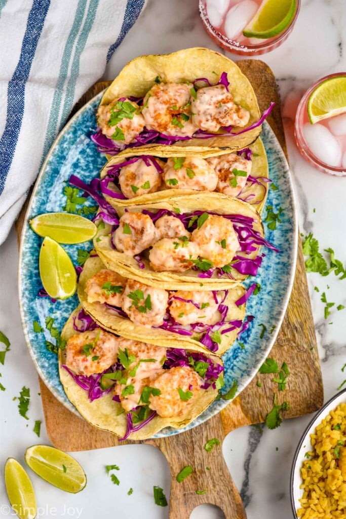 Overhead photo of Bang Bang Shrimp Tacos with lime wedges for garnish.