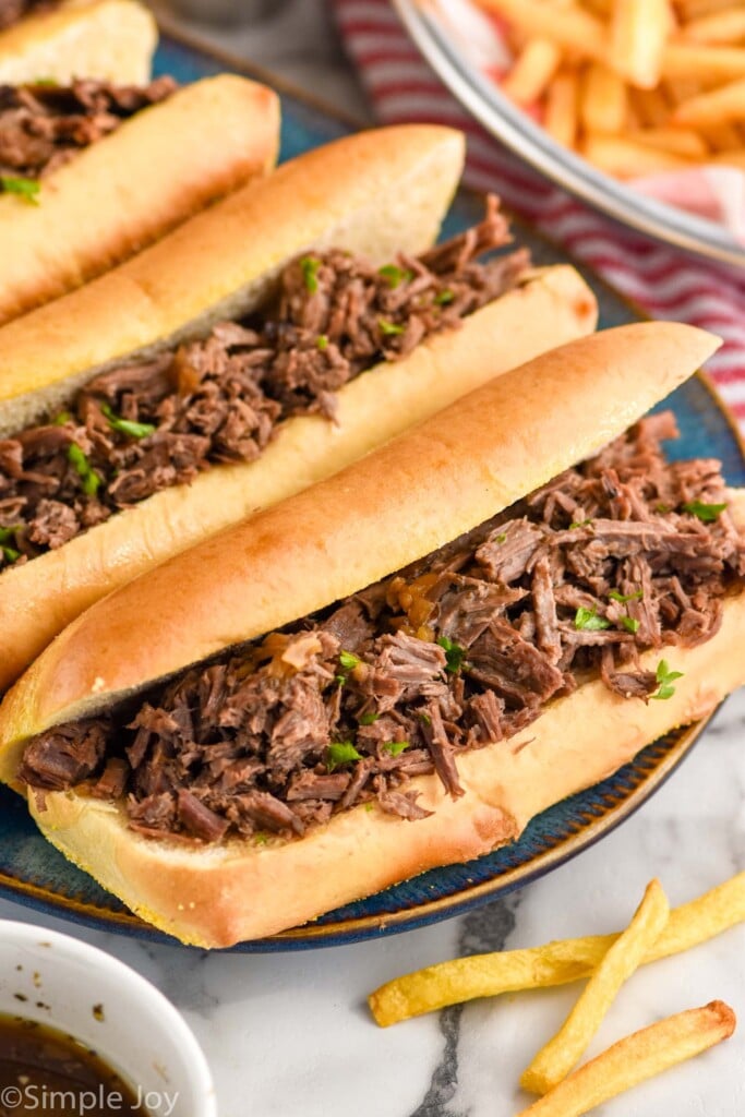 Overhead photo of a platter of French Dip Sandwiches. French fries on the side.