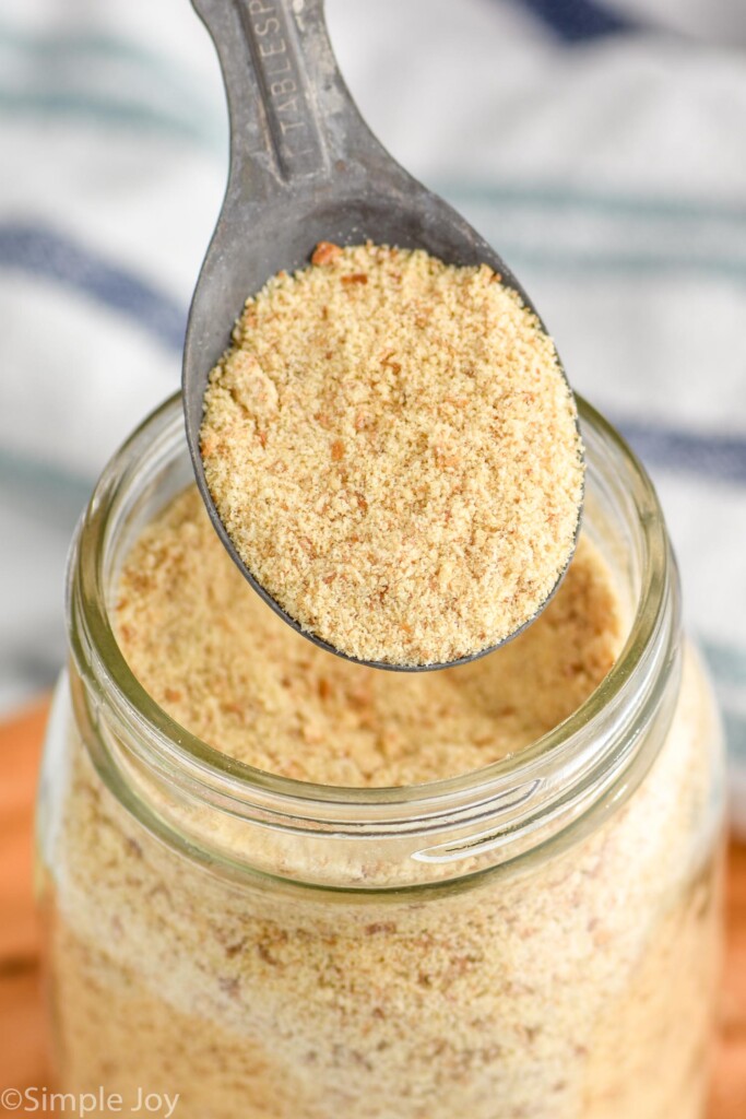 Close up photo of a measuring spoon scooping Breadcrumbs out of a mason jar.