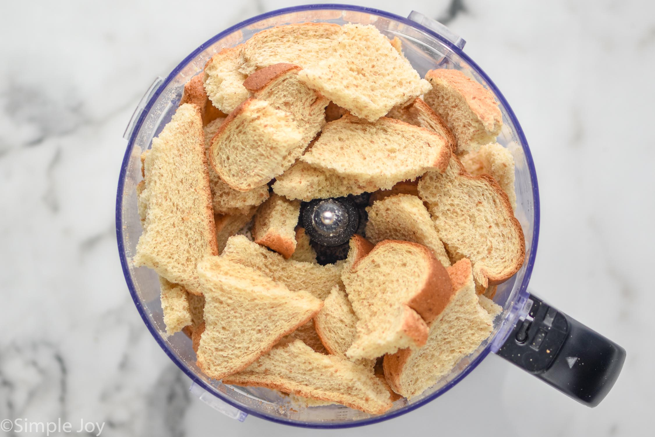 Overhead photo of bread in a food processor for Breadcrumbs recipe.