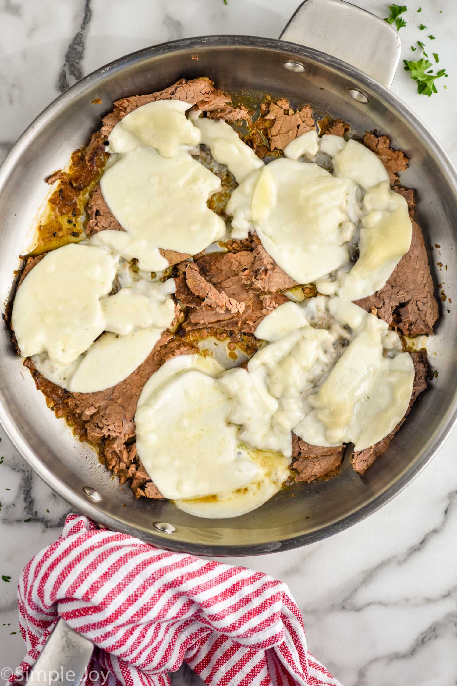 Overhead photo of meat and cheese in pan for French Dip Sandwich recipe.