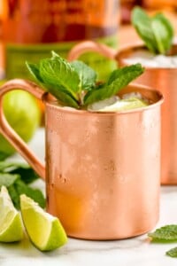 Photo of Kentucky Mules served in copper mugs and garnished with lime slices and mint leaves.