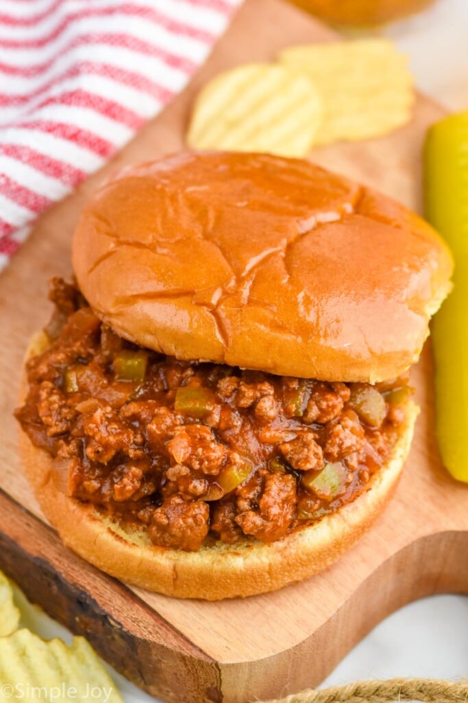 Overhead photo of Homemade Sloppy Joes sandwich served with potato chips and a pickle spear.