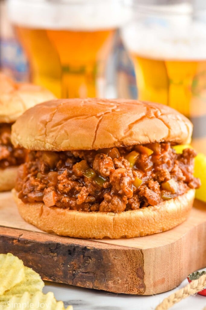 Close up photo of Homemade Sloppy Joes sandwiches with glasses of beer in the background.