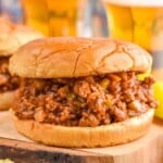 Close up photo of Homemade Sloppy Joes sandwiches with glasses of beer in the background.