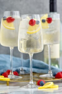 Photo of White Wine Spritzers garnished with lemon slices and berries.