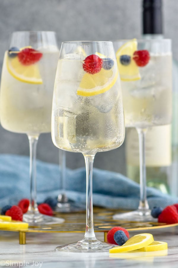 Photo of White Wine Spritzers garnished with berries and lemon wedges.