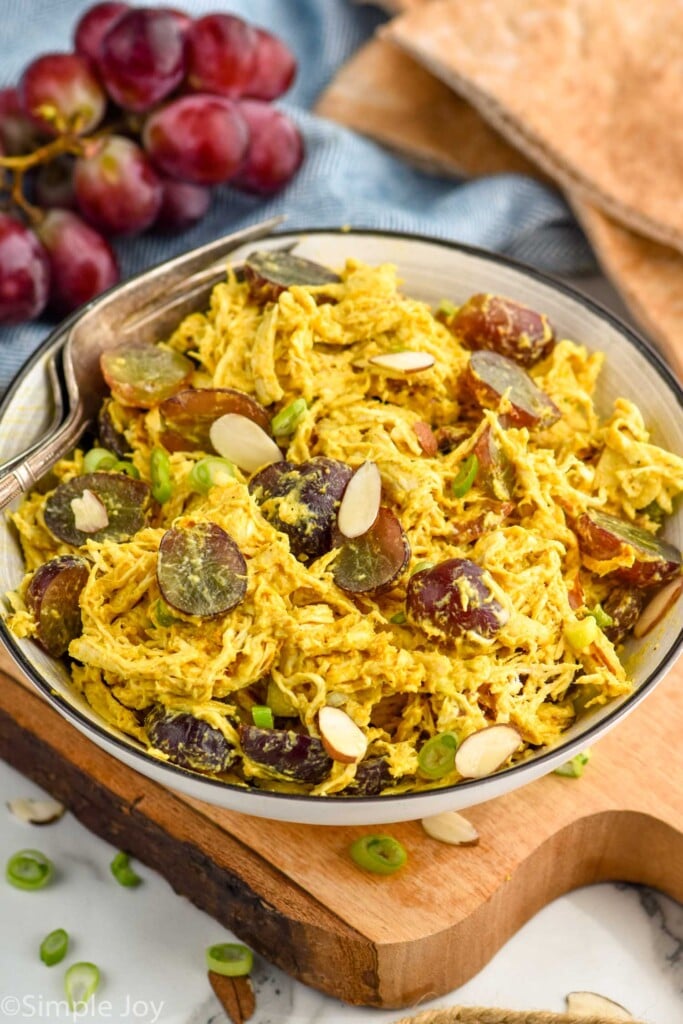 Overhead photo of a bowl of Curry Chicken Salad. Grapes in background.