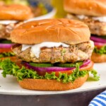 Close up photo of Greek Turkey Burgers served on buns with yogurt sauce, lettuce, tomato, onion, and pickles. - 10