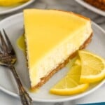 Pinterest graphic for Lemon Cheesecake recipe. Image is overhead photo of a slice of Lemon Cheesecake served on a plate with a fork and garnished with lemon slices. Text says, "Lemon Cheesecake simplejoy.com"