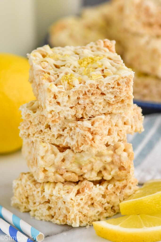 Close up photo of a stack of Lemon Rice Krispie Treats next to slices of lemon.