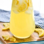 Pinterest graphic for Lemonade recipe. Image is photo of a pitcher of homemade Lemonade garnished with lemon slices. Text says, "Homemade Lemonade simplejoy.com"