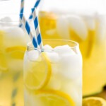 Pinterest graphic for Lemonade recipe. Text says, "the best homemade Lemonade simplejoy.com." Image is close up photo of a glass of Lemonade garnished with lemon slices. Glass has two straws for drinking.