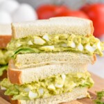 Close up photo of a stack of two Avocado Egg Salad sandwiches cut in half.