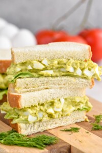 Close up photo of a stack of two Avocado Egg Salad sandwiches cut in half.