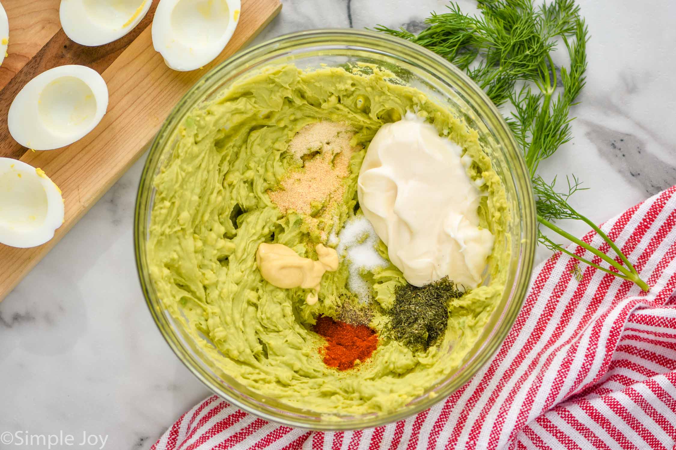 Overhead photo of a mixing bowl of ingredients for Avocado Egg Salad recipe.