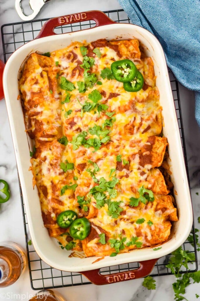 Overhead photo of a baking dish of Beef Enchiladas on a cooling rack.