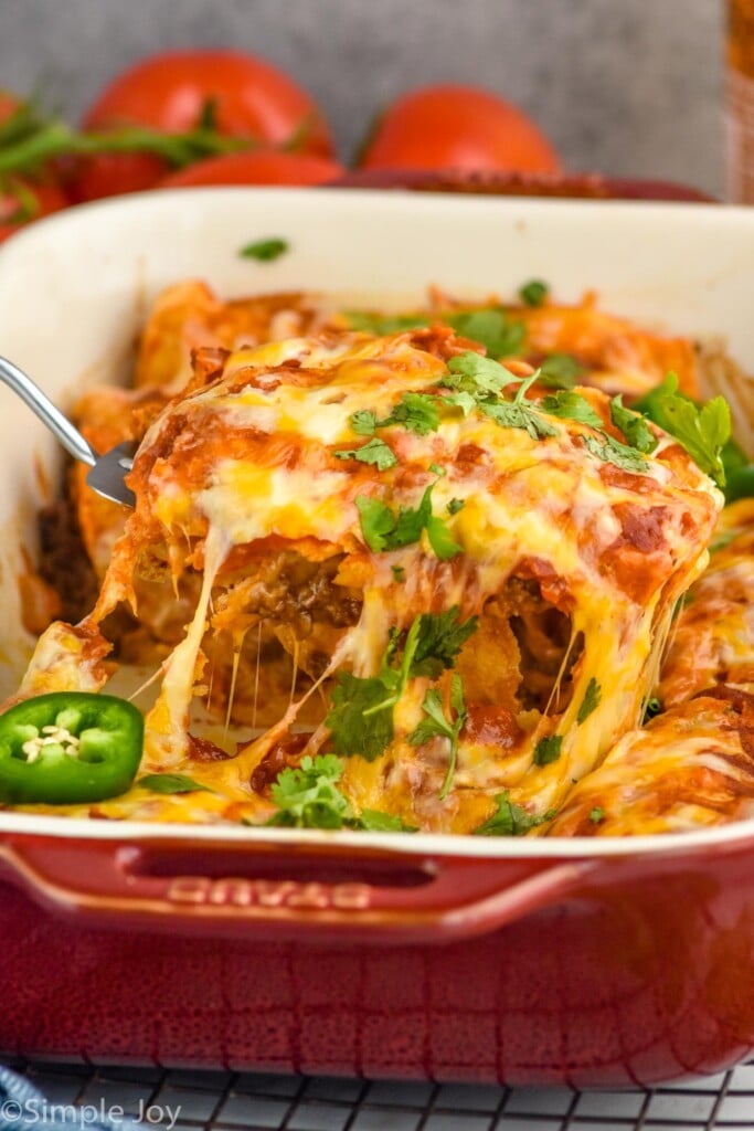 Close up photo of spatula serving a slice of Beef Enchiladas from baking dish.