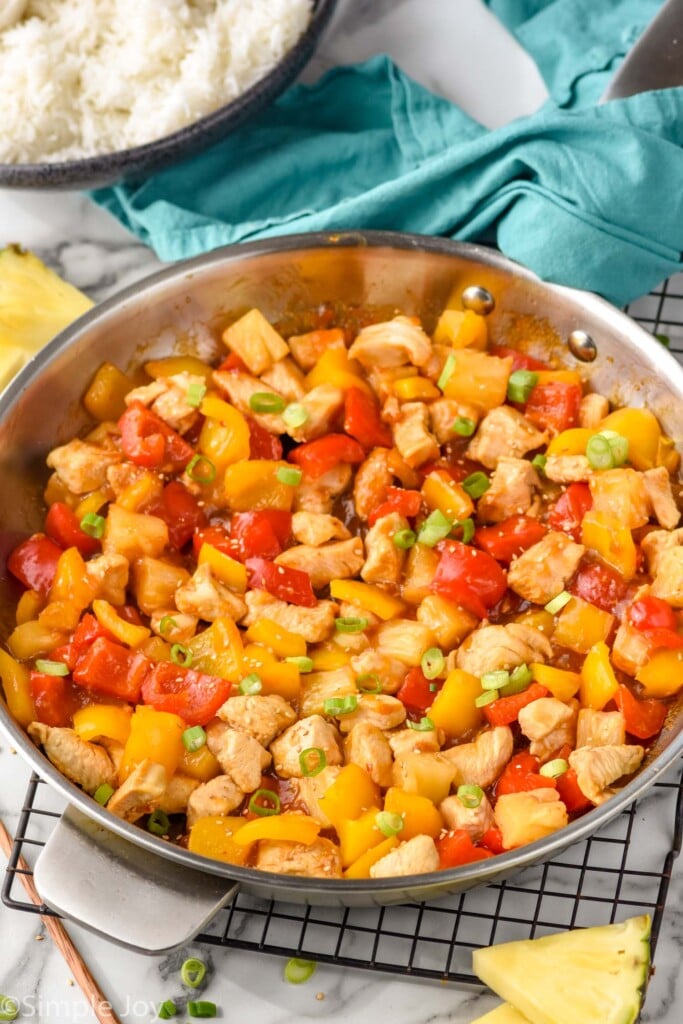 Overhead photo of Pineapple Chicken in a skillet. Bowl of rice beside skillet.