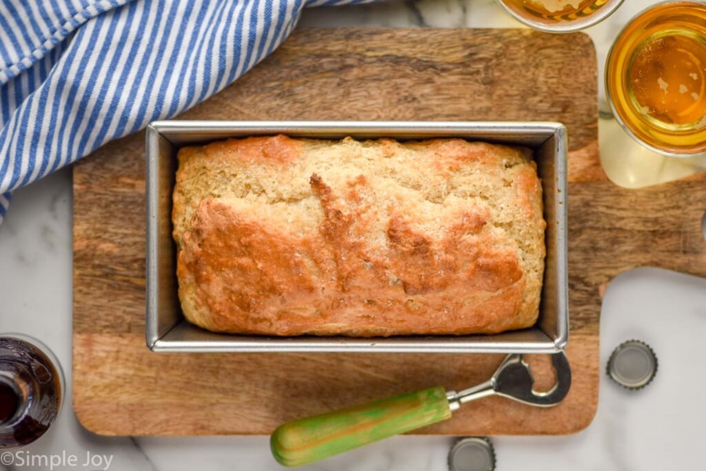 Overhead photo of a loaf of Beer Bread. Glasses of beer beside cutting board and loaf pan.