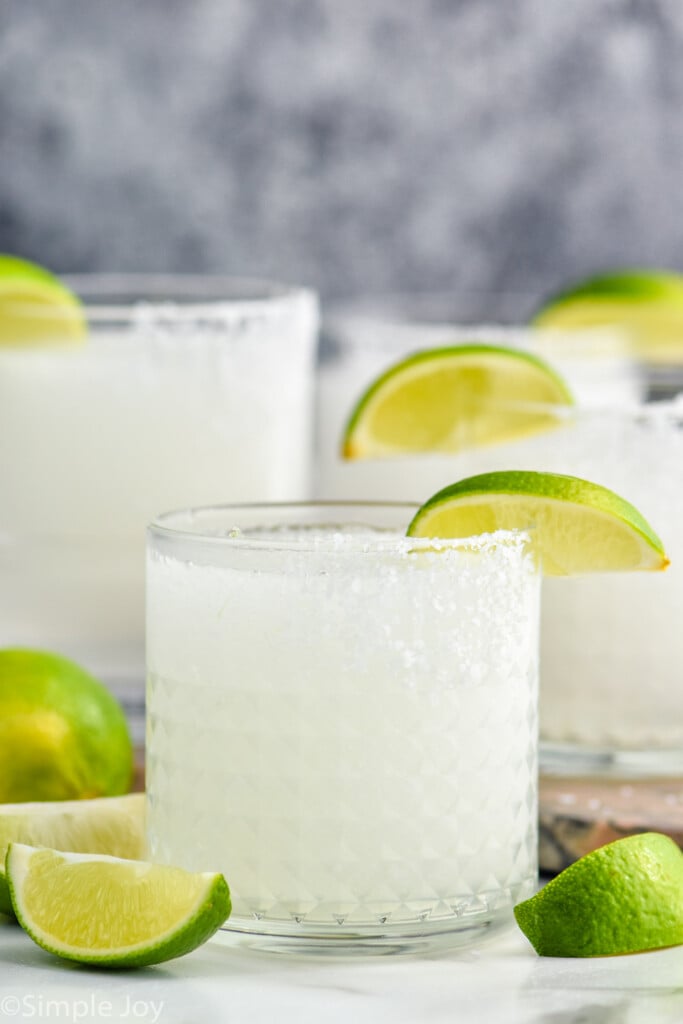 Close up photo of glasses of Frozen Margarita recipe garnished with lime slices.