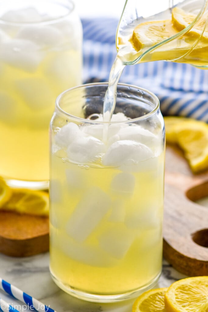 Photo of a pitcher of homemade Lemonade being poured into a glass of ice.