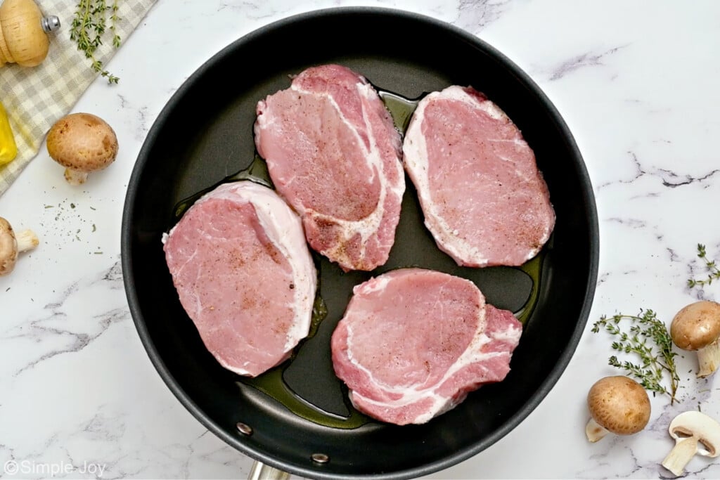 overhead of four pork chops in a skillet