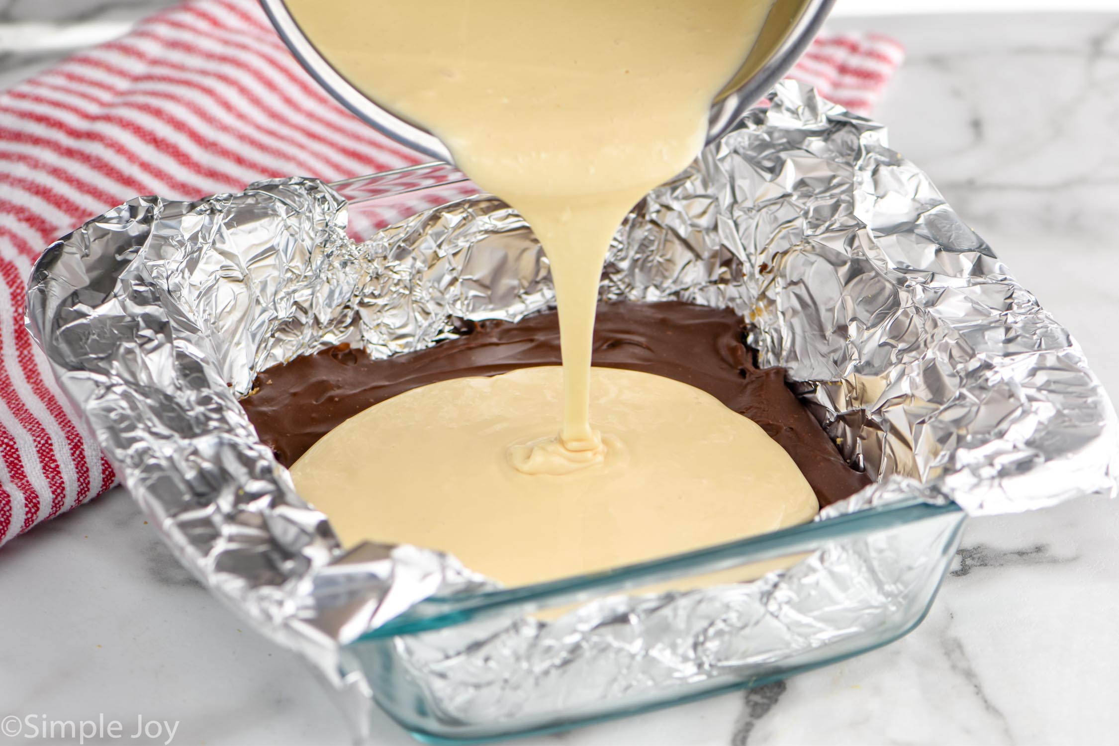 Overhead photo of marshmallow layer being poured into dish for S'mores Fudge recipe