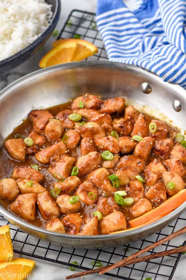 sideview photo of Orange Chicken recipe in a skillet garnished with green onions
