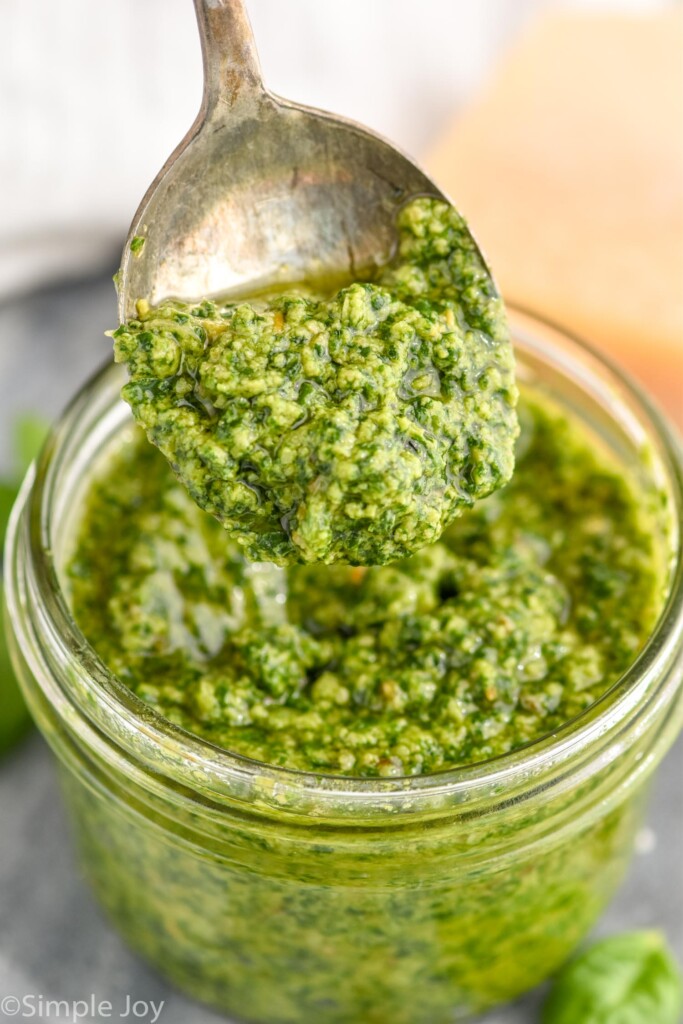 Overhead photo of a jar of Pesto Sauce Recipe with a spoon scooping out some pesto sauce