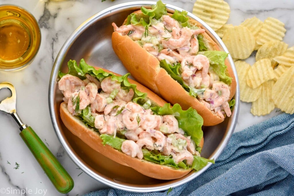 Overhead photo of two Shrimp Salad sandwiches, potato chips, and a glass of beer.