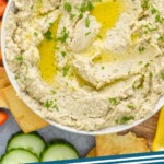 Pinterest graphic for Baba Ganoush. Image shows an Overhead view of a bowl of Baba Ganoush surrounded by slices of cucumber and pepper and pita chips for serving. Text says "baba ganoush simplejoy.com"