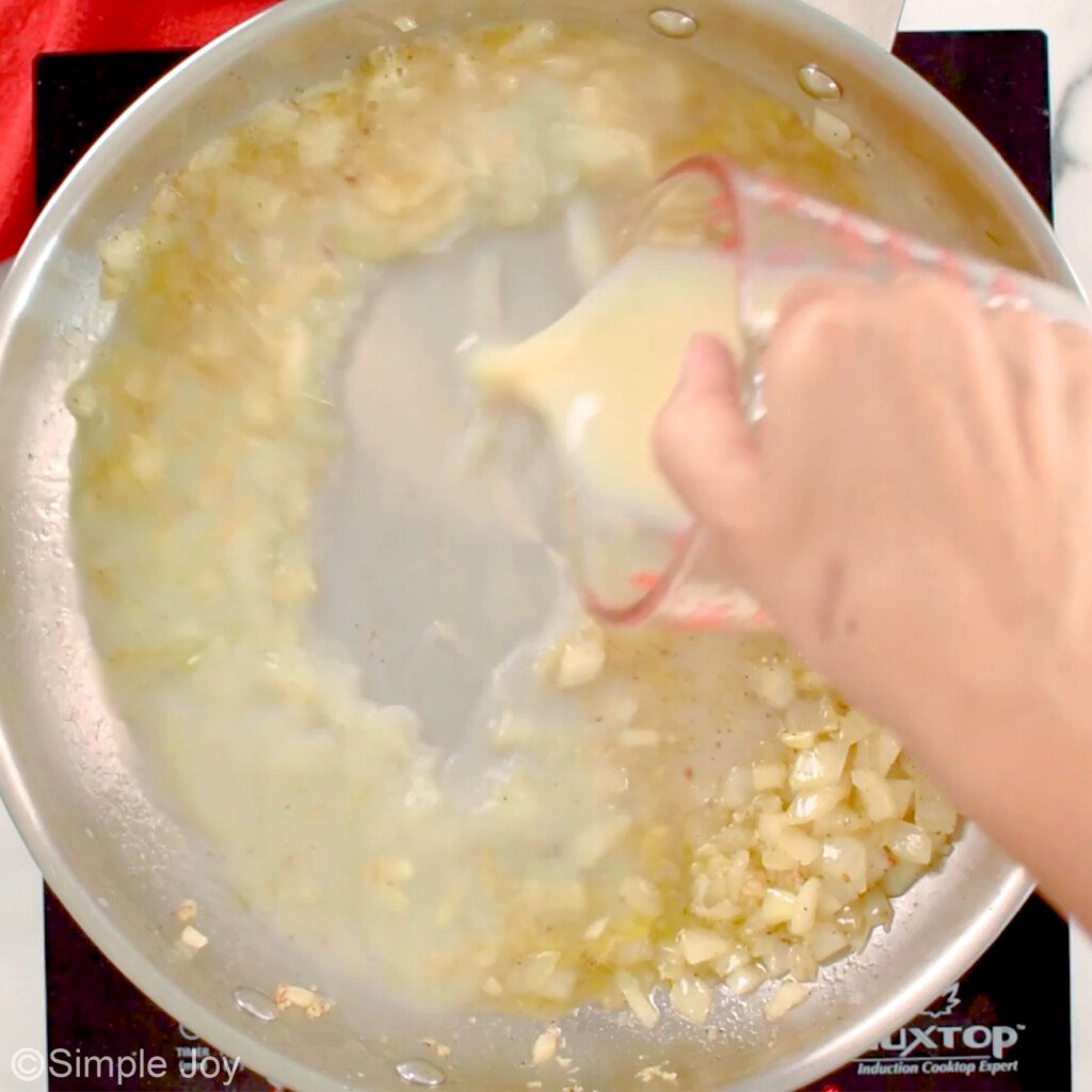 clam juice being added to a skillet
