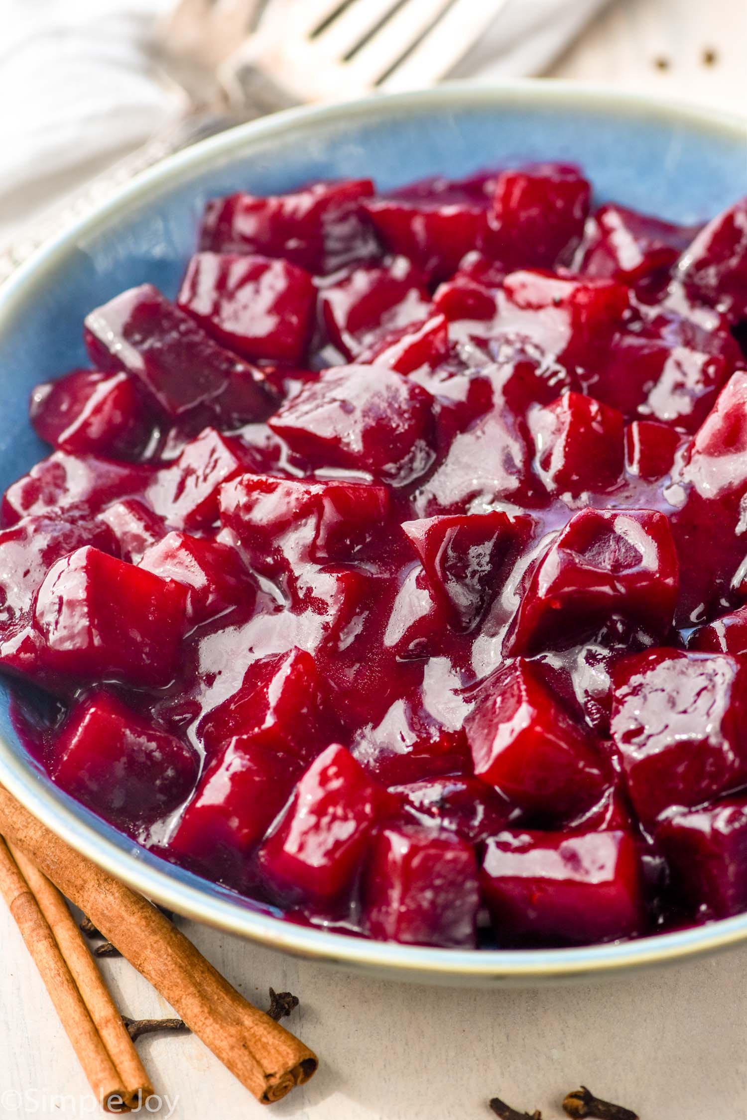 bowl of harvard beets with two cinnamon sticks sitting beside