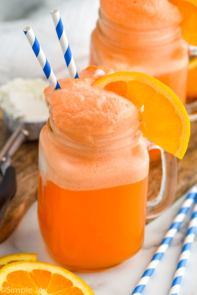 Summer cocktail in glass with orange slice and drinking straw