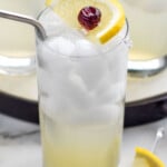 Glass of Tom Collins cocktail with ice, lemon cherry garnish, and straw - 9