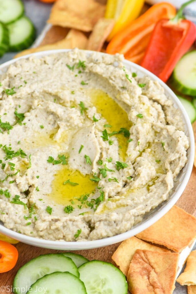 Bowl of Baba Ganoush surrounded by slices of cucumber and pepper and crackers for serving