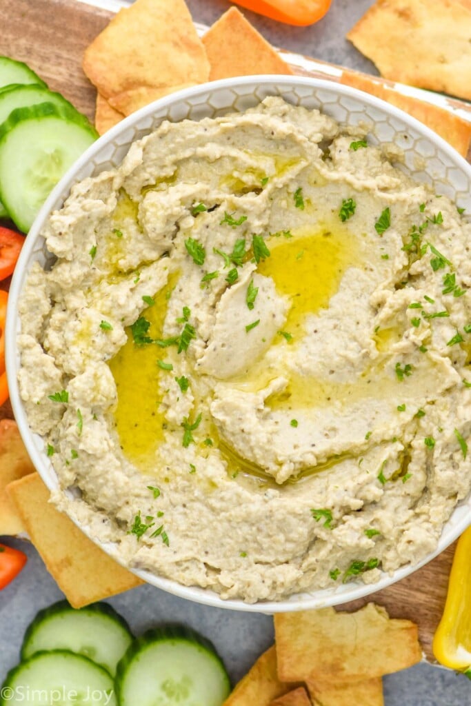 Overhead view of a bowl of Baba Ganoush surrounded by slices of cucumber and pepper and crackers for serving