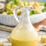 container of homemade Caesar dressing recipe. Bowl of caesar salad and croutons sitting in background - 9